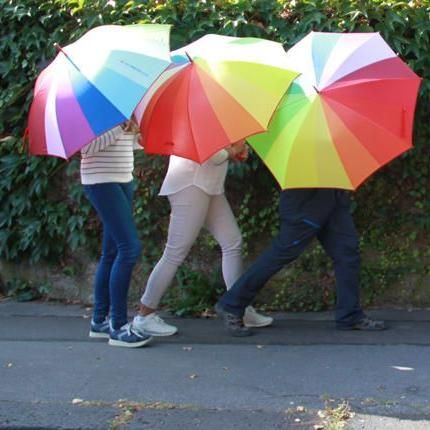 Drei Personen hinter Regenschirmen